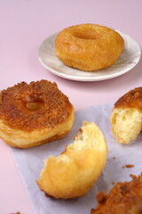 Grainy Donat or Donut or Doughnut with caramel and Lotus biscuit crumbs. Selective focus, pink pastel background