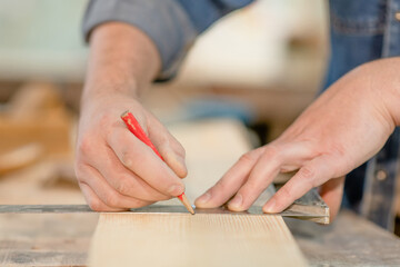 Obraz na płótnie Canvas Close up man's hands taking measurement of a wooden plank