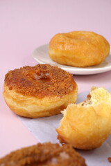 Naklejka na ściany i meble Grainy Donat or Donut or Doughnut with caramel and Lotus biscuit crumbs. Selective focus, pink pastel background