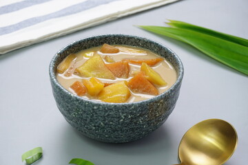 Close up look Kolak Ubi Nangka or Sweet potato and Jack fruit compote is popular Indonesian dessert made from Sweet potato cooked with coconut milk, palm sugar and pandanus leaves. Gray background