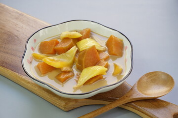 A plate of Kolak Ubi Nangka or Indonesian dessert made from Sweet Potato and Jack fruit as a compote. Based on coconut milk, palm sugar and Pandanus leaves in isolated gray background