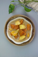 Top view of Kolak Ubi Nangka or Indonesian dessert made from Sweet Potato and Jack fruit as a compote. Based on coconut milk, palm sugar and Pandanus leaves in isolated gray background