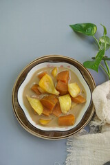 Top view of Kolak Ubi Nangka or Indonesian dessert made from Sweet Potato and Jack fruit as a compote. Based on coconut milk, palm sugar and Pandanus leaves in isolated gray background