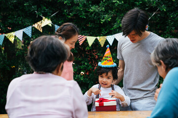 Asian family celebrate kid birthday party together outdoor at yard.