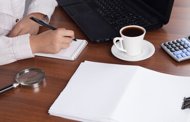 Obraz na płótnie Canvas Young businesswoman working in an office with a cup of coffee.