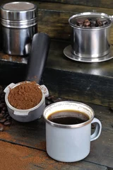 Fotobehang coffee bean cup and porta filter with coffee powder inside and Vietnam Drip Coffee on wooden table © PG2020
