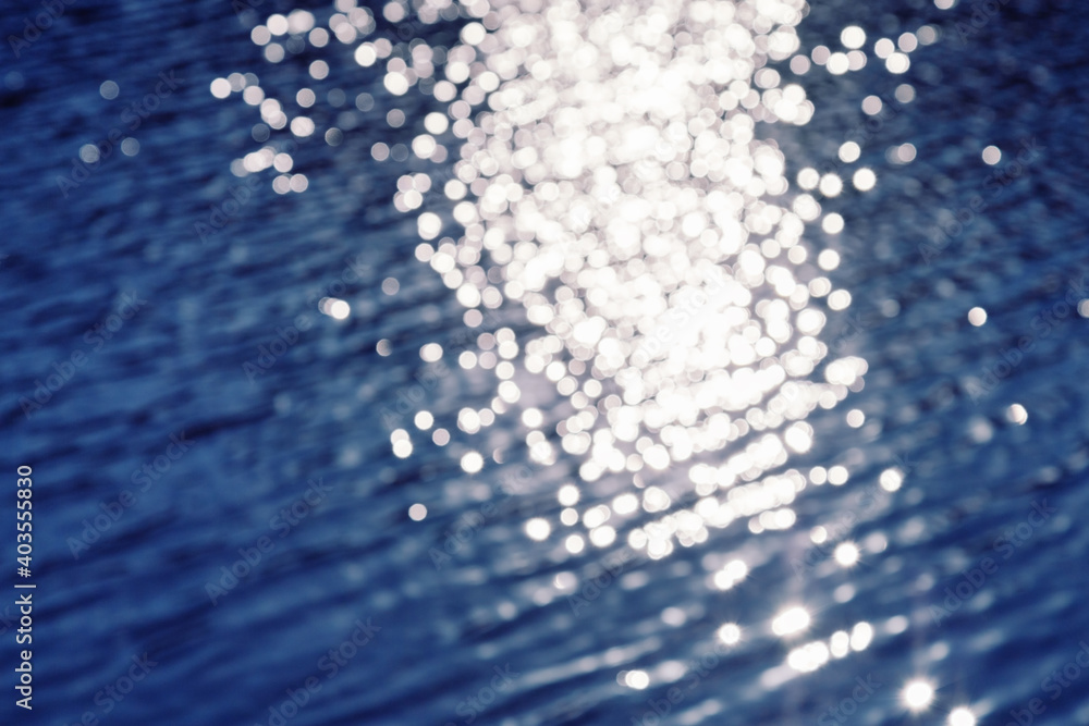 Wall mural natural background with blue water surface with path of sunlight reflection. bokeh pattern texture.