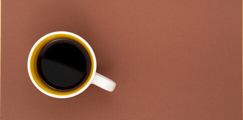 Top view, flat lay of black coffee cup on background brown.