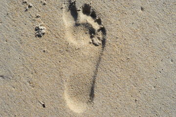 Fototapeta na wymiar Natural background of sand with the imprint of a human foot.