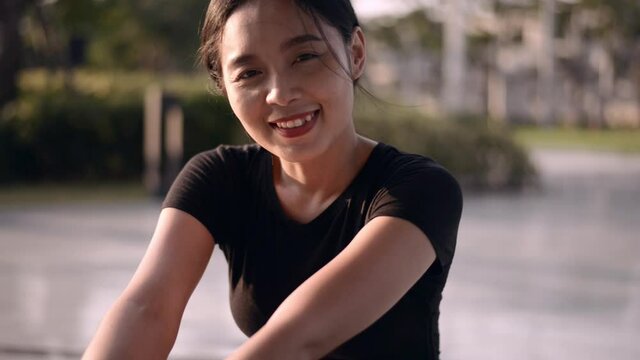 Shot of beautiful fii woman smiling outdoors. Fitness woman sitting after workout.