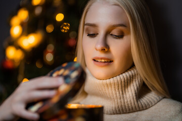 Girl in a cozy sweater opens a Christmas present