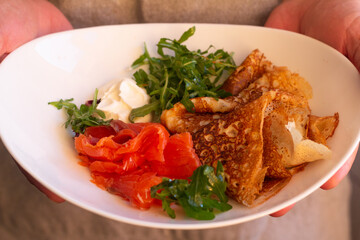 pancakes and fish in hands close up