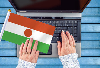 woman hands and flag of Niger on computer, laptop keyboard 