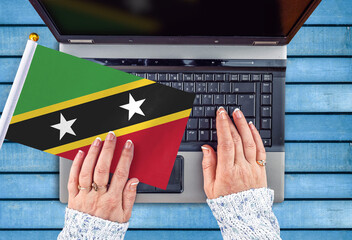 woman hands and flag of Saint Kitts and Nevis on computer, laptop keyboard 