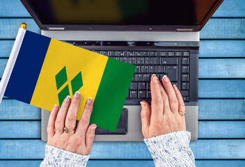 woman hands and flag of Saint Vincent and the Grenadines on computer, laptop keyboard 