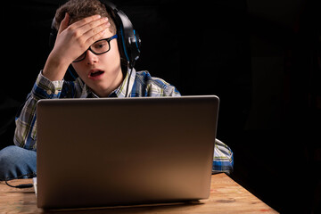 Boy doing school at home with shirt and glasses on laptop