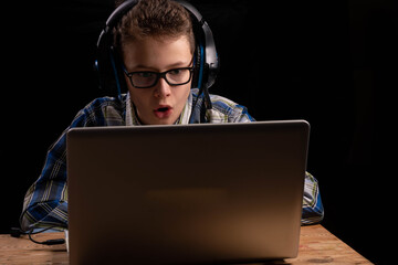 Boy doing school at home with shirt and glasses on laptop