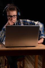 Boy doing school at home with shirt and glasses on laptop