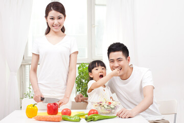 Obraz na płótnie Canvas A happy family of three preparing a salad 