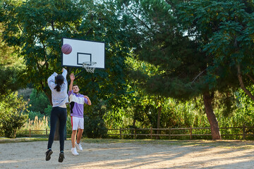 young couple playing one on one basketball, girl makes a basket