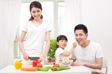 Obraz na płótnie Canvas A happy family of three preparing a salad 