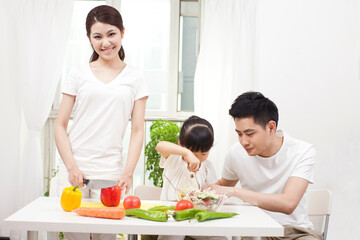 Obraz na płótnie Canvas A happy family of three preparing a salad