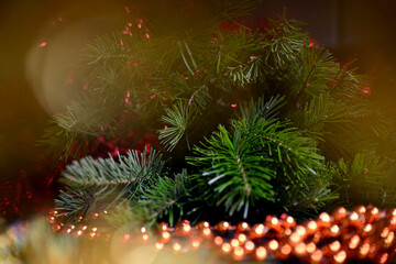 Fototapeta na wymiar Winter background for New Year and Christmas, fir branches, tinsel, Christmas tree decoration, orange beads, blurry lights.