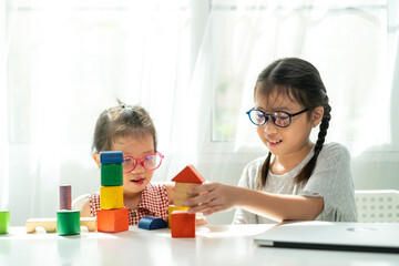 Asian girl spend quality time together for playing wooden block toy with her sister in living room at home. Asian family and kids concepts