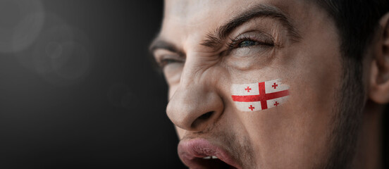 A screaming man with the image of the Georgia national flag on his face