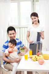 Obraz na płótnie Canvas Happy family making juice with electric juicer