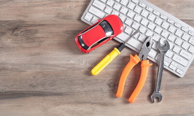 Toy car, wrench, screwdriver, pliers and computer keyboard.