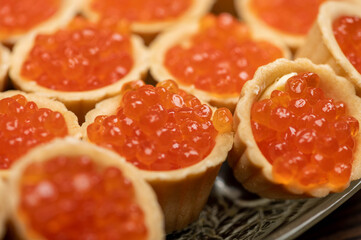 Tartlets with salmon caviar on a platter. Close-up, selective focus.