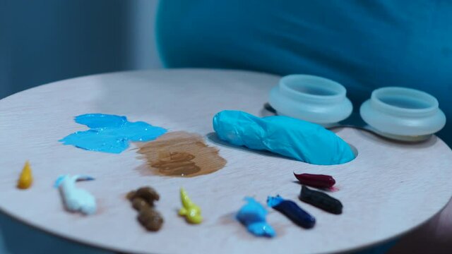 the girl takes the paint with a brush from the palette. close-up palette.
