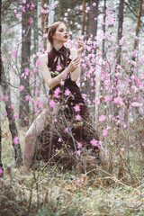 Japanese-style girl in a flowering forest among pink flowers in spring