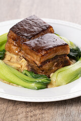Dong Po Pork meat in a white plate with vegetable on wooden background.