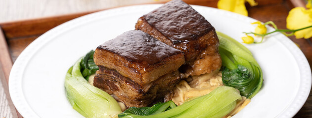 Dong Po Pork meat in a white plate with vegetable on wooden background.