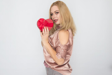 dreaming woman in pink blouse holding red gift box heart