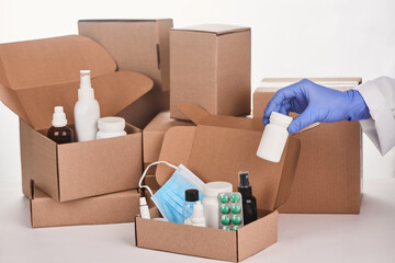 Pharmacist's hand in glove putting a bottle of pills into a cardboard box