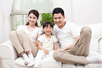 A happy family of three sitting in couch