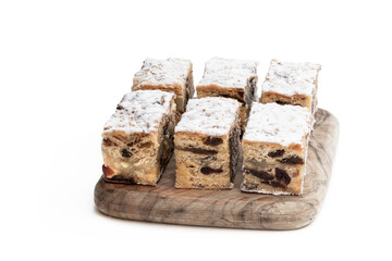 Christmas stollen slices with icing sugar on wooden board isolated on white