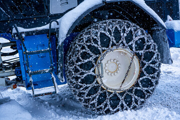 Closeup of a chained wheel of a snowy snow plow on the mountain ski resort in french Alps