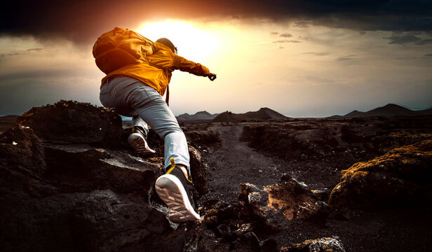 Successful man hiking mountains at sunset - Hiker with backpack pointing the sky with finger