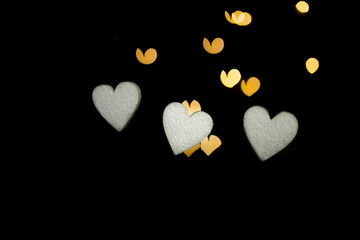 dark background with bokeh of white and gold hearts in a light blur