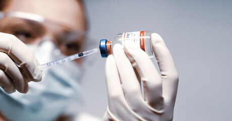  Doctor holding a syringe with a single bottle vial of Covid-19 vaccine and she is ready for...