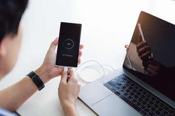 Man hands holding smartphone charging battery from notebook type c port with using pd charging technology