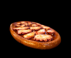 Octopus slices over clay tray and black background