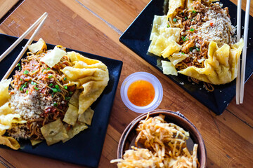 Devil noodle called (Mie Gacoan) equipped with fried dim sum and vegetables toppings