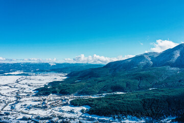 Obraz premium Alpine village, ski resort city, houses covered with snow, sunny winter day in mountain valley.