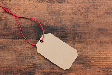 Blank price tag on wooden table background. Overhead view of kraft paper gift tag. Copy space	