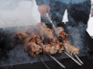 Men fry on the street in winter on skewers on coals and open fire. Blurred image from steam and smoke.